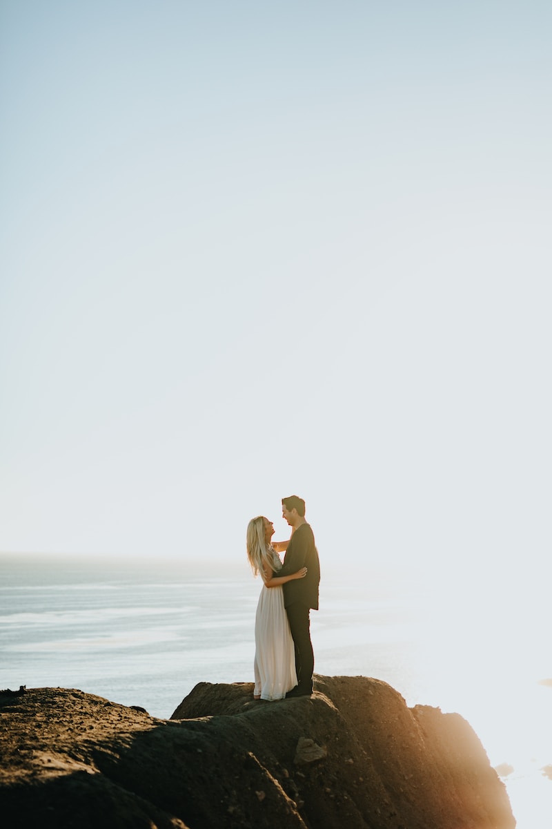 woman and man standing on brown rock formation during daytime