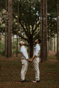 a couple of men standing next to each other in a forest