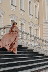 a woman in a long dress walking down some stairs